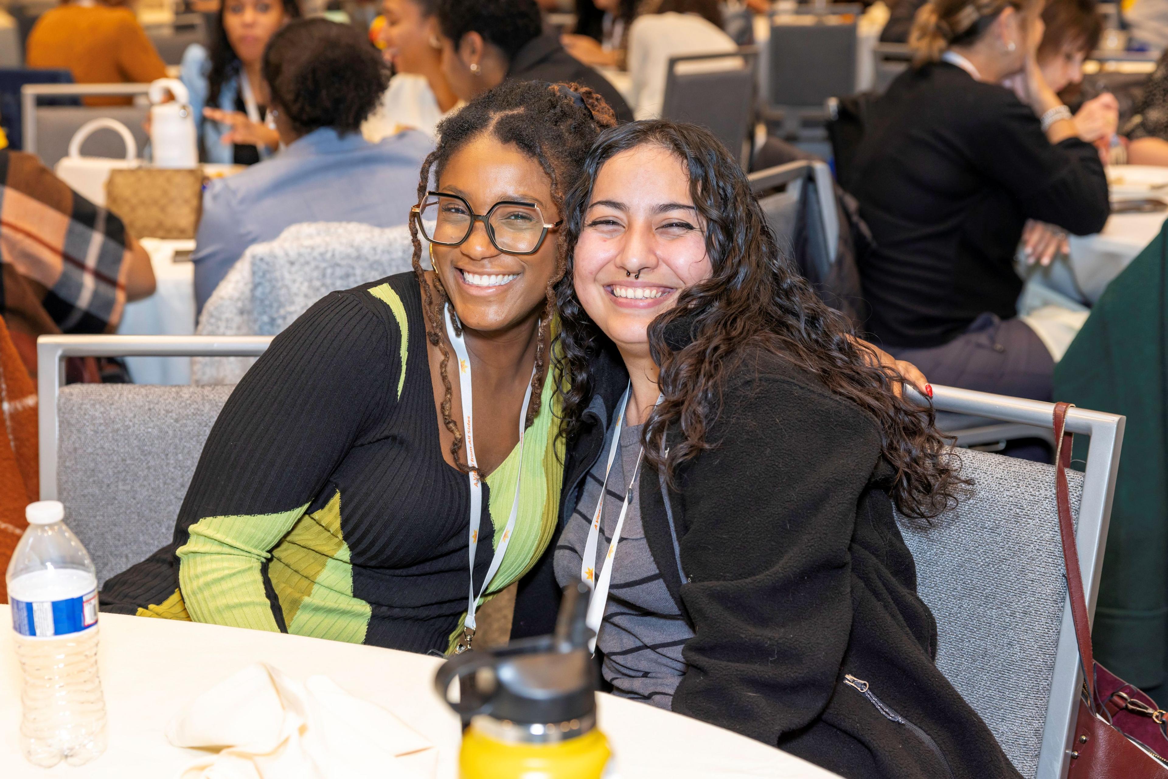 Picture of two attendees sitting at a table in the Grand Ballroom smiling.