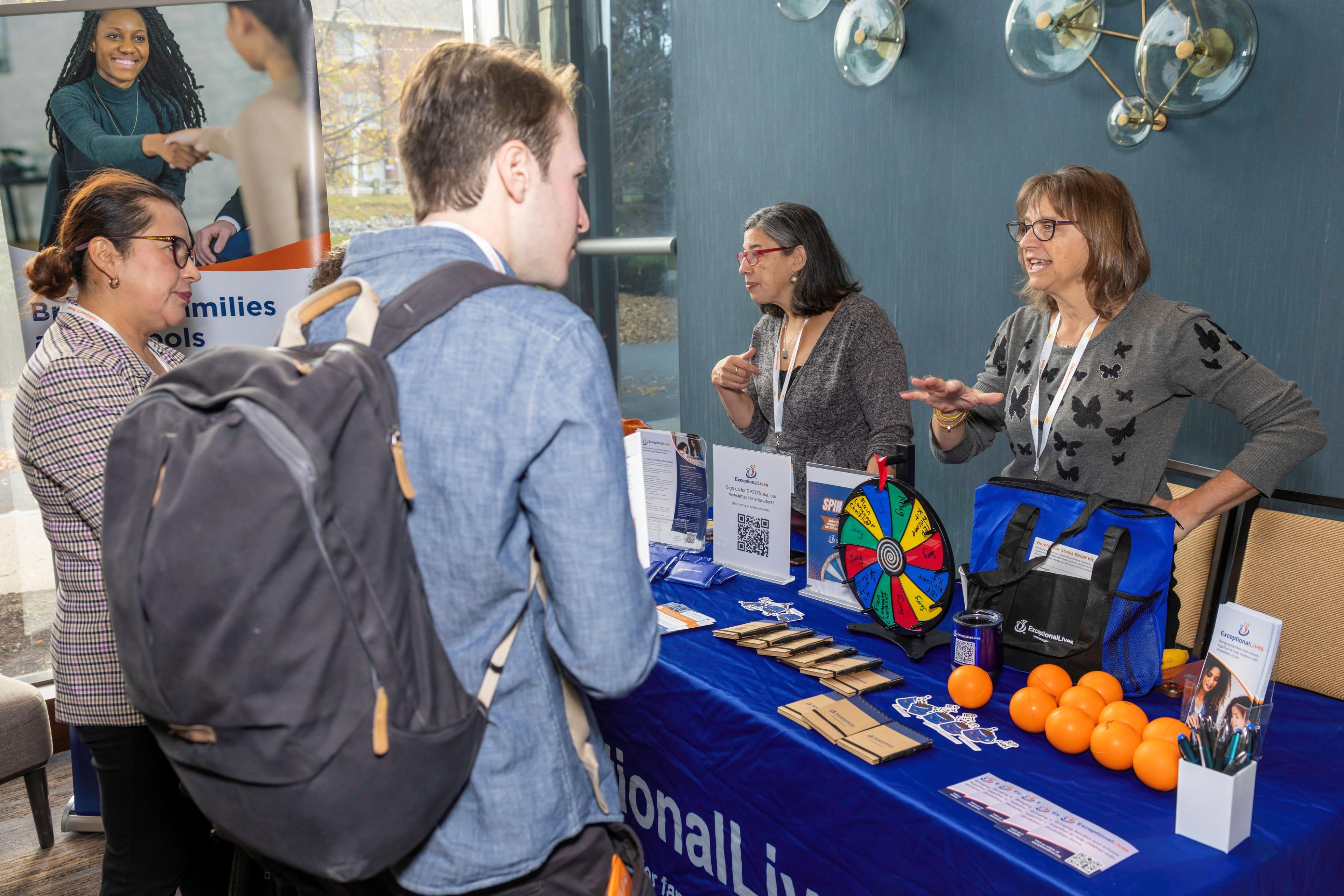 Picture of two attendees speaking with the Exceptional Lives Exhibitors.